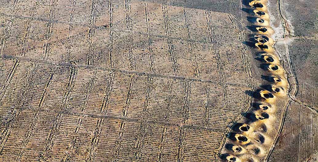 A line of evenly spaced spoil craters in Iraq is the only evidence of a subterranean man-made water stream called a qanat, first constructed by the Persians during the early years of the first millennium BCE. Photo: © Alireza Teimoury