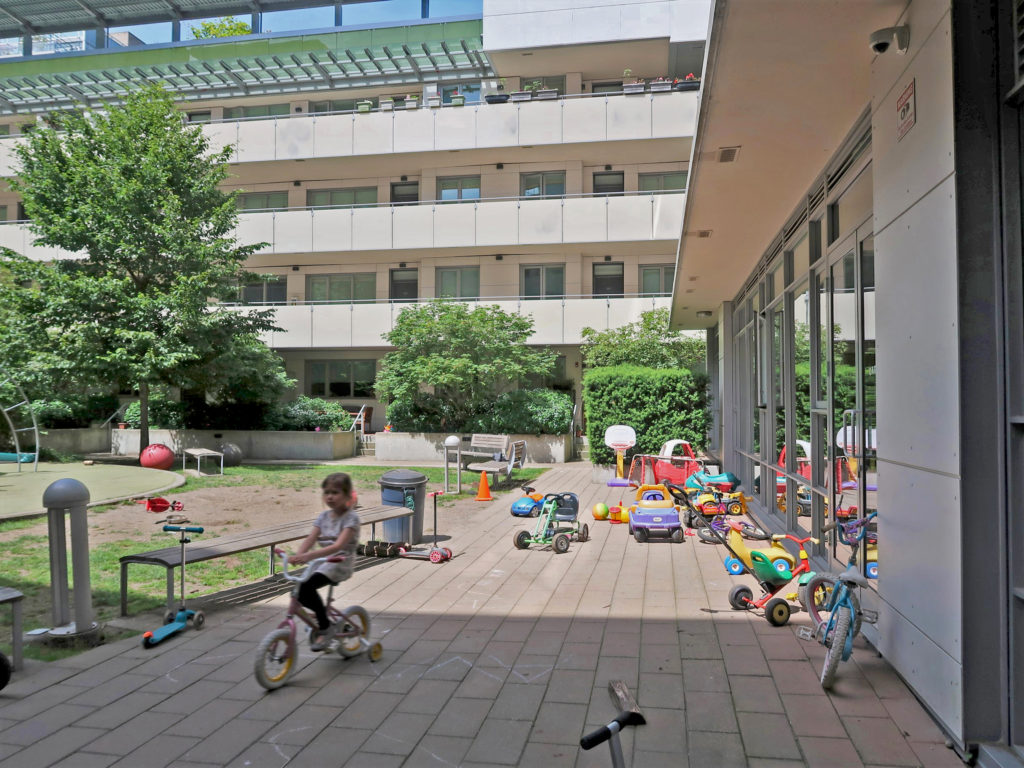 Children playing in a residential courtyard with scattered shared toys, Vancouver.