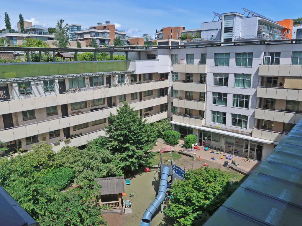 Residential courtyard with communal playspace overlooked by apartments, Vancouver.